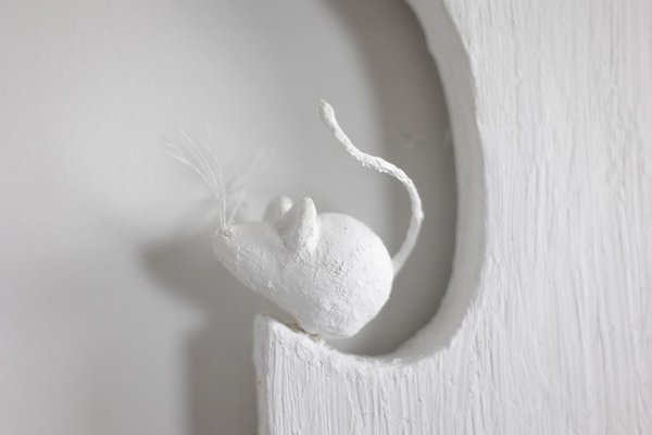 gatto nero di fronte ad un piccolo specchio quadrato sopra il letto bianco Foto stock