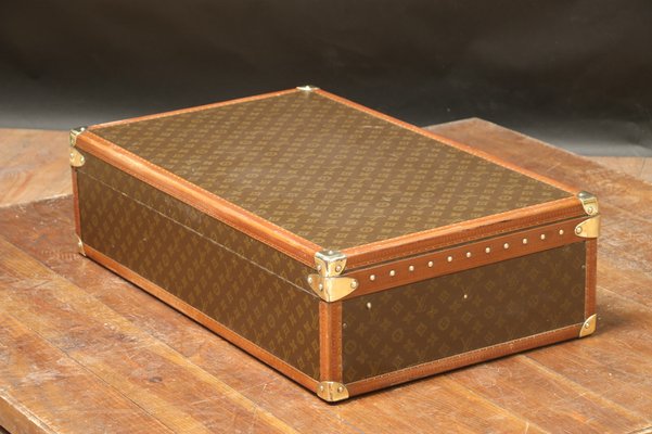 A Louis Vuitton wardrobe trunk, covered in LV monogram canvas and bound in  leather and brass with wooden banding, the lock marked D, the interior  fitted with four drawers, including a hat