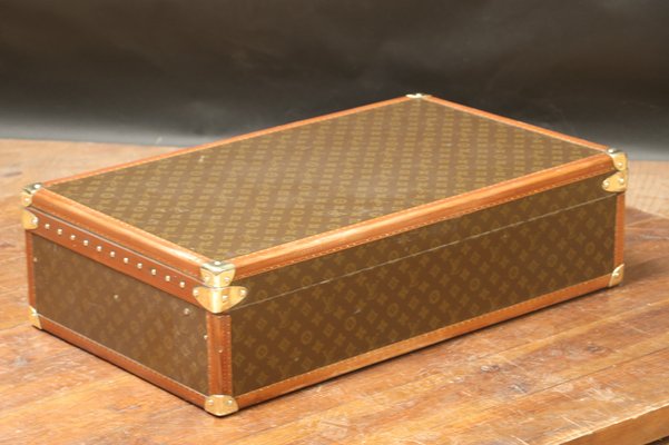 A Louis Vuitton wardrobe trunk, covered in LV monogram canvas and bound in  leather and brass with wooden banding, the lock marked D, the interior  fitted with four drawers, including a hat