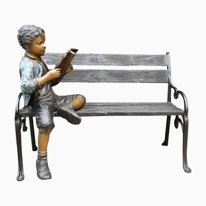 Banco de jardín de bronce con estatua de niño