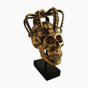 Totenkopfskulptur mit goldener Krone auf Sockel