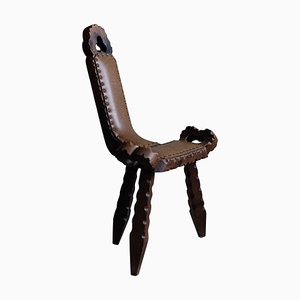 Silla trípode de madera tallada con asiento de cuero, década de 1890