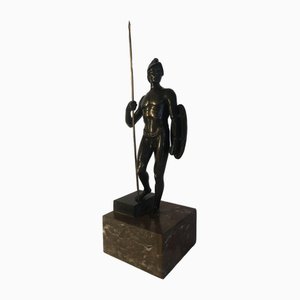 Escultura de soldado de bronce con casco, lanza y escudo sobre base de mármol, años 20
