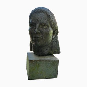 Busto de mujer joven sobre bloque de pizarra, años 60