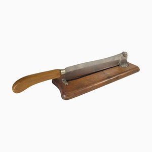 Cuchillo para pan francés de madera y acero sobre plato de madera, siglo XX