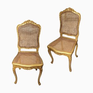 Sillas francesas de madera dorada con respaldo y asiento de rejilla. Juego de 2