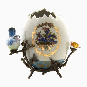 Uovo in ceramica con uccellino e fiore con base in bronzo