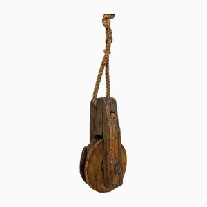 Polea antigua rústica de madera desgastada con cuerda, década de 1890