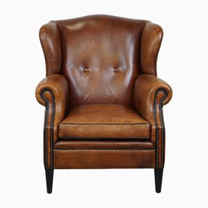 Fauteuil à oreilles en cuir avec clous et passepoil noir