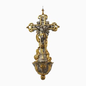 Cruz religiosa de metal plateado y dorado con agua bendita