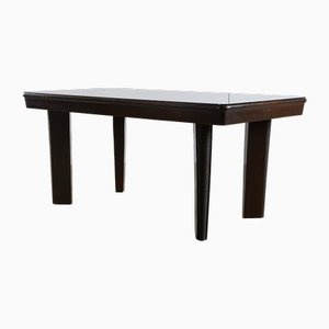 Mesa de comedor grande y robusta con patas talladas y superficie de vidrio