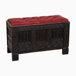 Banco inglés con tallas de madera y asiento acolchado de tela roja