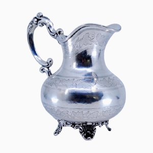 Silberner Wasserkrug mit gravierten Pflanzenmotiven, Henkel und erhöhten Füßen