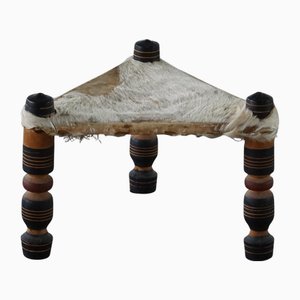 Taburete africano vintage triangular hecho a mano con tres patas con asiento de piel de vaca, años 40
