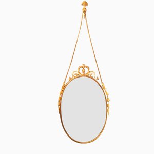 Espejo vintage ovalado de latón con decoración ornamental